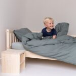 Mit einem breiten Lächeln im Kinderbett sitzend
