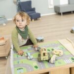 Betzold Teppich für einen Bodenspieltisch - 2er-Set - Junge, der am Spieltisch mit Stadtteppich und Autos auf dem Tisch sitzt