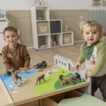 Betzold Teppich für einen Bodenspieltisch - 2er-Set - Jungen, die mit afrikanischen Tieren auf dem Landschaftsteppich spielen