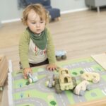 Betzold Teppich für einen Bodenspieltisch - 2er-Set - spielender Junge mit Autos auf Stadtteppich mit einzelnen Autos