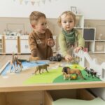 Betzold Teppich für einen Bodenspieltisch - 2er-Set - spielende Kinder mit Landschaftsteppich auf Spieltisch und afrikanischem Tier-Set
