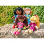 Stoffpuppen – 4er-Set – sitzend und stehend draußen auf einem Felsen mit grünem Hintergrund