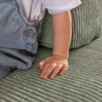 Nahaufnahme des olivgrünen Cordstoffs am Jindl Spielsofa mit einer Kinderhand