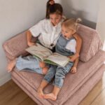 Gemeinsam auf dem Spielsofa in Zartrosa sitzen und lesen